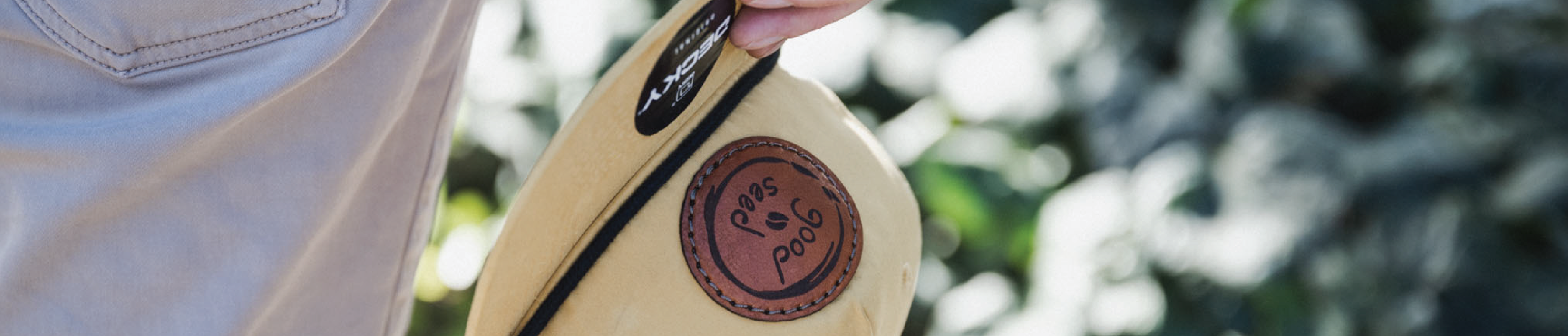 man holding a custom leather patch hat that says Good Seed on the patch