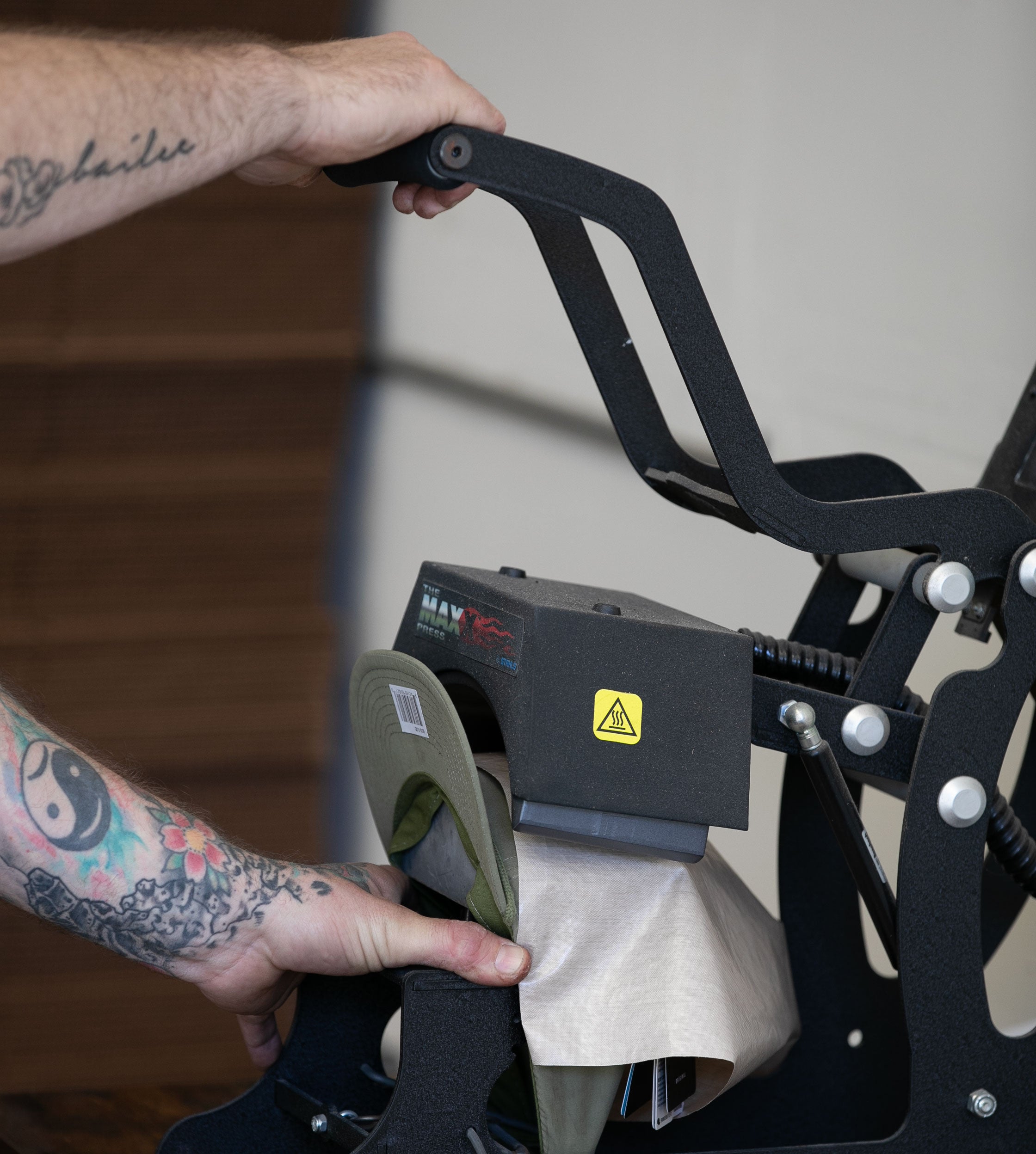 Man demonstrating using a heat press to attach a leather patch onto a hat