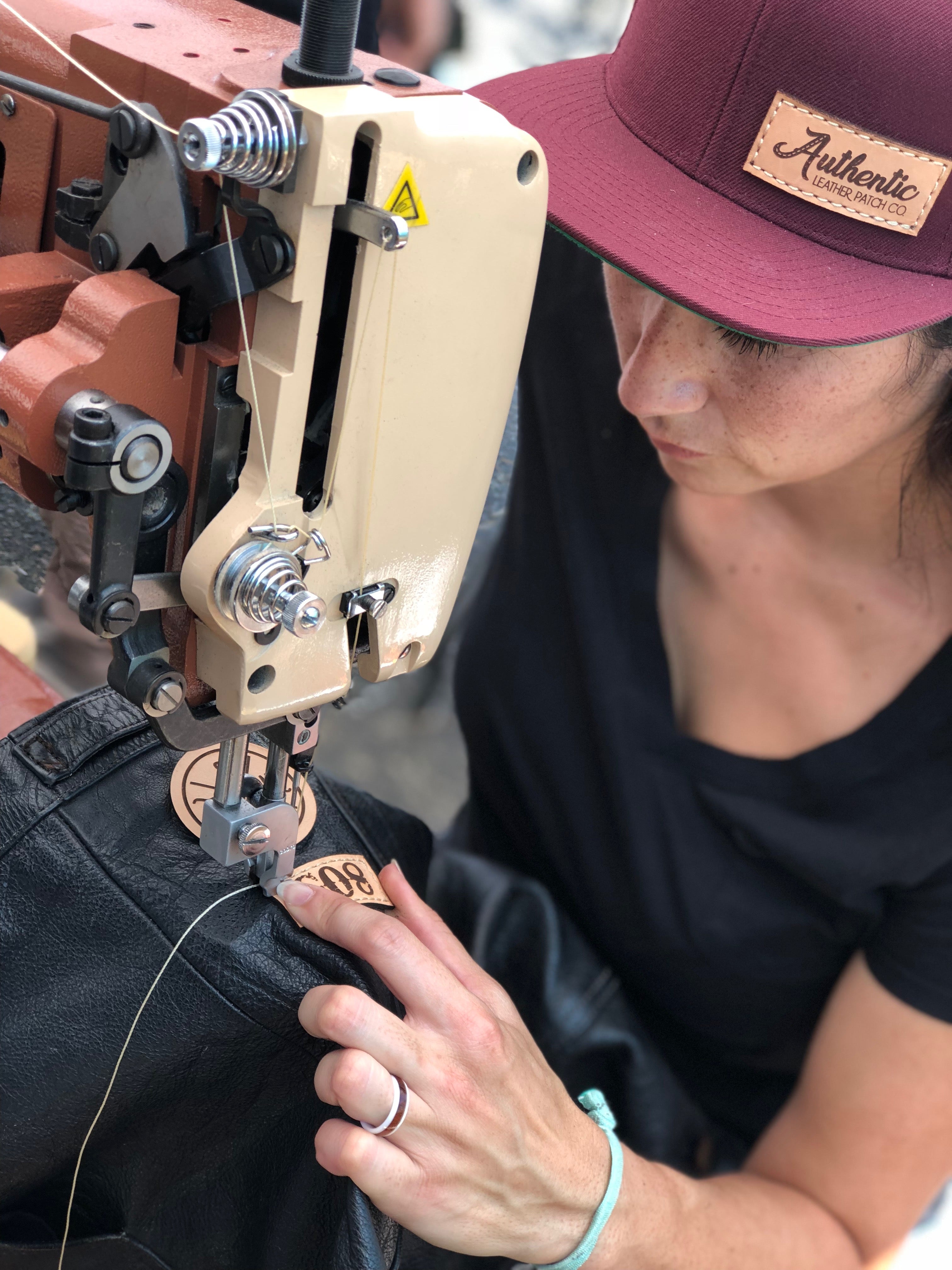 Woman stitching patches onto a motorcycle vest using a saddle stitcher