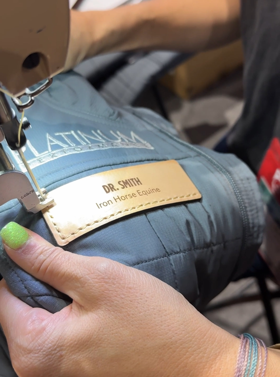 Close up of custom leather patch getting sewn onto a vest at AAEP in San Diego