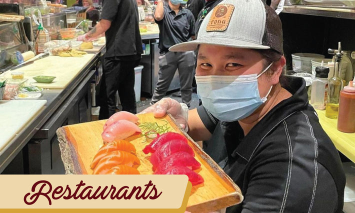 Custom leather patch hat featured on a sushi maker showing off a dish with salmon, tuna and a white fish